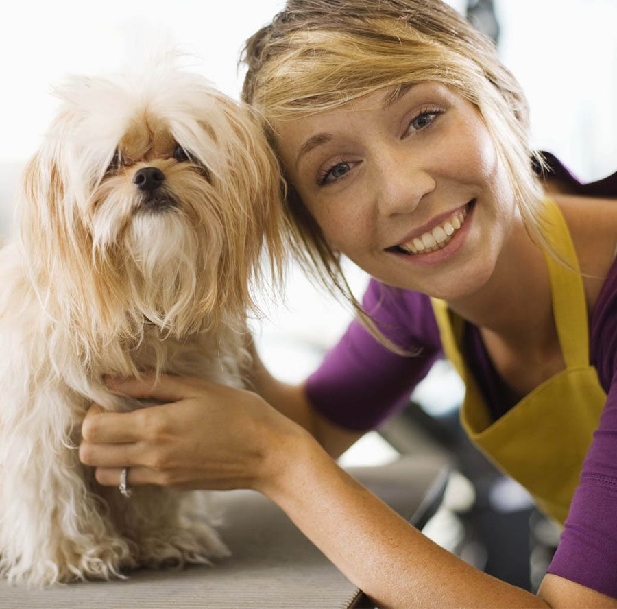 Homepage - Smiling Dog Groomer Portrait with a Small Dog